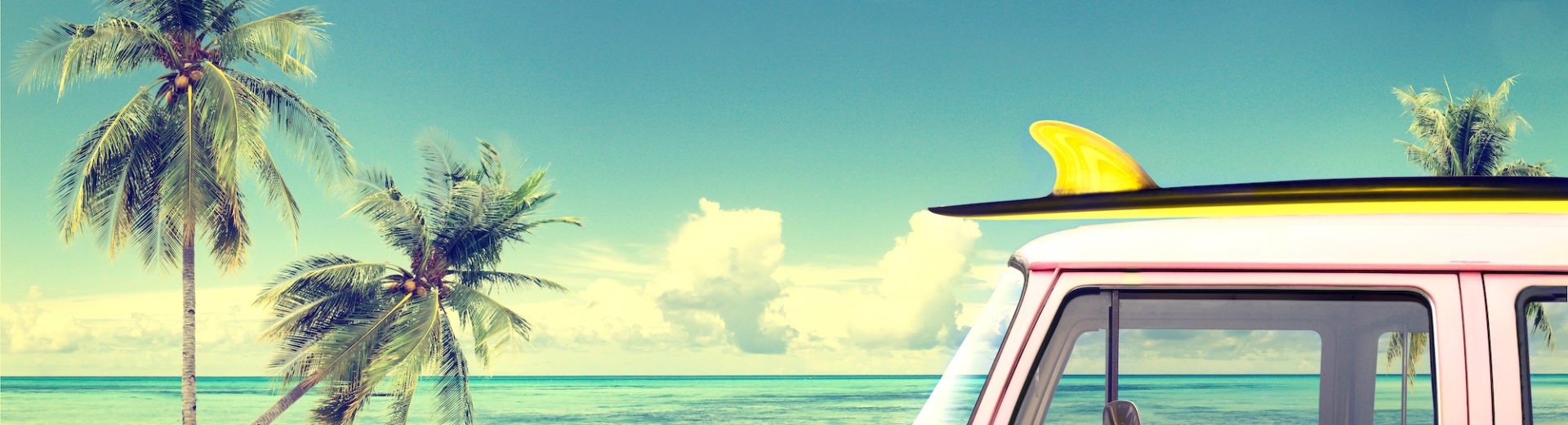 Van with surfboard driving on tropical beach road